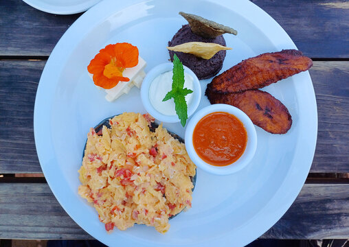 Desayuno t&iacute;pico Guatemalteco, servido con huevos revueltos sobre una tortilla negra, frijoles negros, queso y platos fritos. Toma Superior.