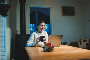 Smiling happy woman working on laptop while sitting at table. Young creative woman working and typing on keyboard at home. Work at home concept - obrazy, fototapety, plakaty