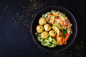 Meatballs served with white rice and marinated sliced cucumber on wooden background
