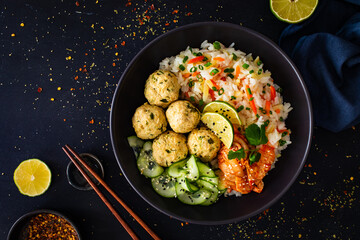 Meatballs served with white rice and marinated sliced cucumber on wooden background
