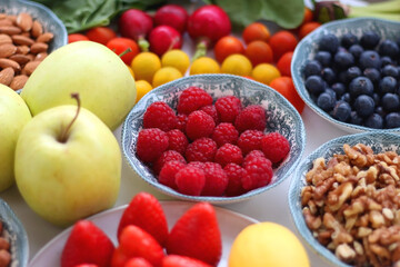 Apples, lemons, bananas, berries, carrots, leek, tomatoes, radishes, spinach and various nuts on white background. Healthy seasonal fruit and vegetable. Selective focus.
