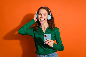 Photo of dreamy excited lady dressed green shirt headphones listening music modern gadget isolated orange color background