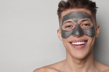 Handsome man with clay mask on his face against light grey background. Space for text