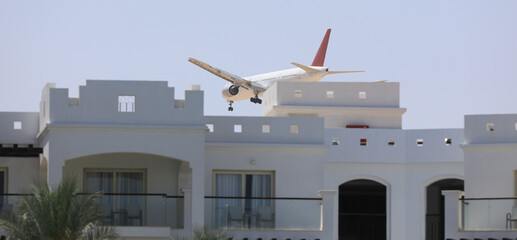 passenger plane lands over a building - obrazy, fototapety, plakaty