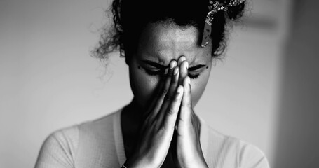 One Overwhelmed Young Black Latina Covering Face with Regret and Anxiety – Struggling with Mental Illness, Suffering 20s African Descent in dramatic black and white, monochrome - obrazy, fototapety, plakaty