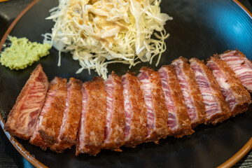 Set of Gyukatsu or beef cutlet served with cabbage. A traditional Japanese food that consists of a deep-fried beef cutlet. on the stone grill