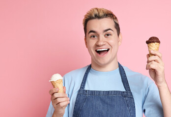 Portrait of happy confectioner holding ice cream cones on pink background