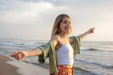 Happy young woman dancing at beach during sunset