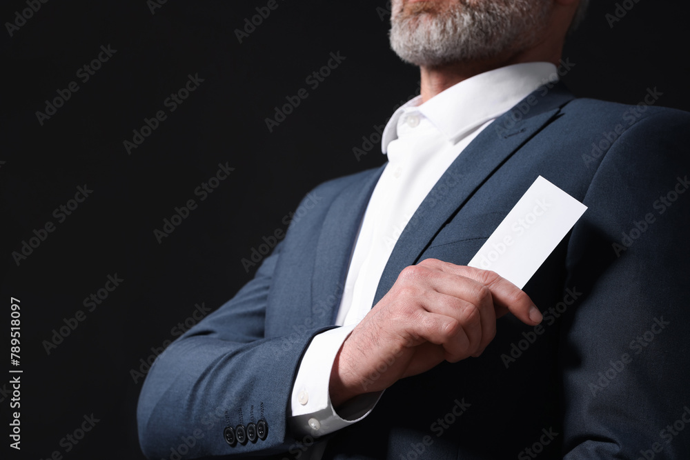 Poster Businessman holding blank business card on black background, closeup. Space for text