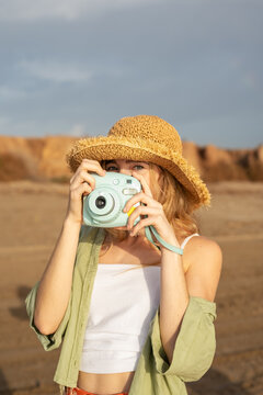Young female photographer taking photos on beach