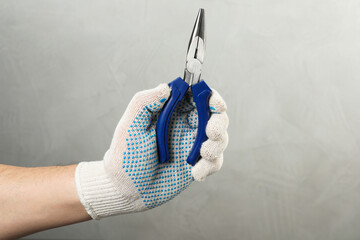Man with needle nose pliers on grey background, closeup