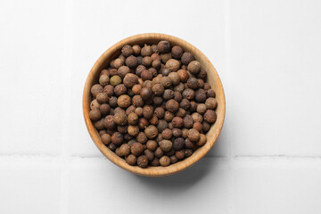 Dry allspice berries (Jamaica pepper) on white tiled table, top view
