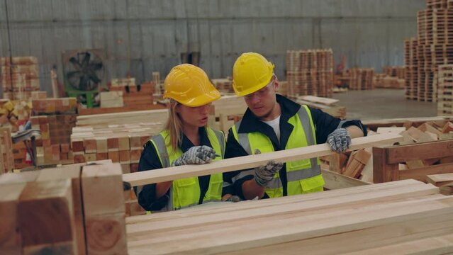 Industrial workers collaboratively checking lumber quality in a factory.