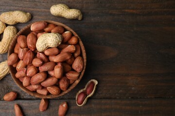 Fresh peanuts in bowl on wooden table, flat lay. Space for text