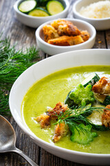 Cream zucchini soup with croutons, Parmesan cheese and fresh dill on wooden table
