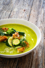 Cream zucchini soup with croutons, Parmesan cheese and fresh dill on wooden table
