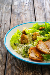 Caesar salad - fried chicken breast and vegetables on wooden table
