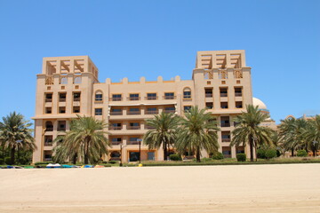 A building with palm trees and a sandy beach