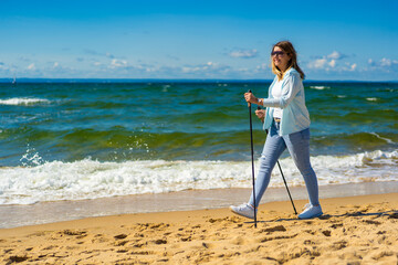 Nordic walking - beautiful woman exercising on beach
