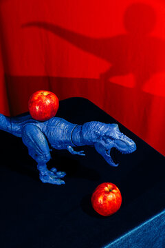 Blue Toy Dinosaur Positioned Next to a Red Apple 