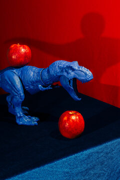 Blue Toy Dinosaur Positioned Next to a Red Apple 