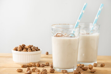 Close-up of two glasses with blue straws with horchata on table with tiger nuts, white background, horizontal, with copy space - obrazy, fototapety, plakaty