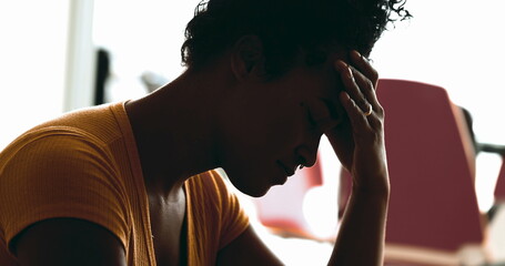 Young African American woman struggles with depression at home in quiet despair feeling overwhelmed by stress and sorrow putting hands on side temples feeling headache - obrazy, fototapety, plakaty