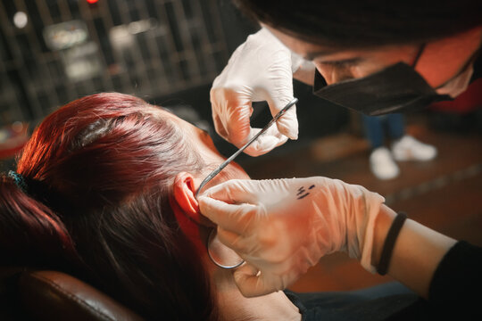 Woman giving a piercing to woman