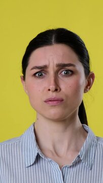 Astonished Caucasian woman exclaiming wow and reacted negatively on yellow background. Dissatisfied and displeasure concept. Vertical video.
