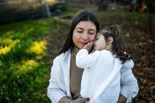 young mother tenderly hugging her daughter in nature