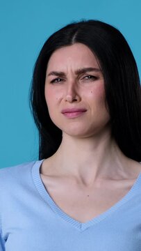 Frustrated and unhappy Caucasian woman smell stinky odor over blue background. Negative reaction and yikes concept. Vertical video.
