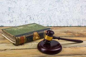 Law concept - Open law book with a wooden judges gavel on table in a courtroom or law enforcement...