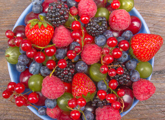 Various summer Fresh berries in a bowl on rustic wooden table. Antioxidants, detox diet, organic...