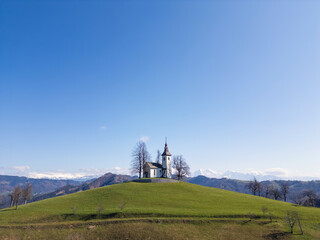 Stunning panoramic view of Julian Alps with iconic hilltop church of Saint Thomas in Slovenia,...