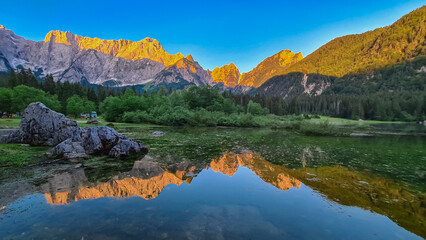 Morning sunrise view of Superior Fusine Lake (Laghi di Fusine) with majestic Mount Mangart in...