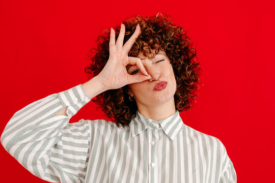 Smiling woman making a funny face while making OK gesture in studio
