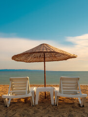 Empty chairs and parasols at beach against sky