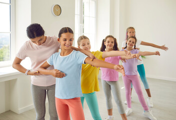 Learning new dance. Teacher of children's dance school helps preteen girls perform choreographic...