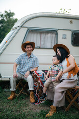 Family Fun in the Great Outdoors: Asian Parents and Cheerful Children Enjoying Summer Camping...