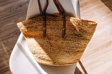 Fashionable jute bag standing on the chair in natural light