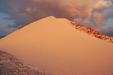 sand dune in the setting sun and dramatic clouds