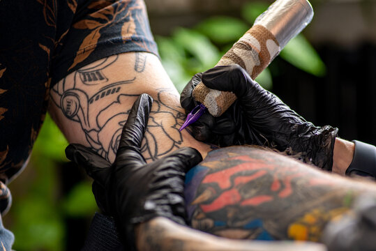 Woman tattoo artist tattooing man in salon