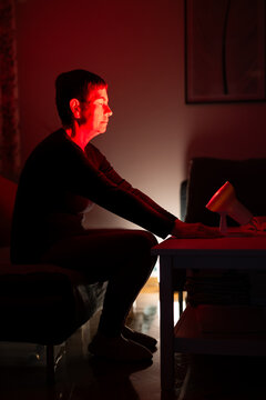 Adult woman using infrared treatment light / lamp at home