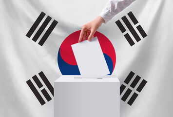Elections, South Korea. A hand throws a ballot into the ballot box. The concept of democracy and...