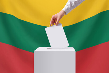 Elections, Lithuania. A hand throws a ballot into the ballot box. The flag of Lithuania on the...