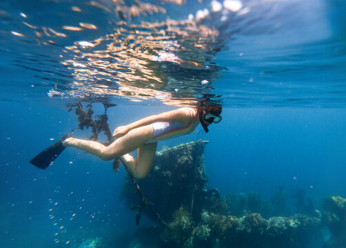 Woman snorkeling next to a sunken ship