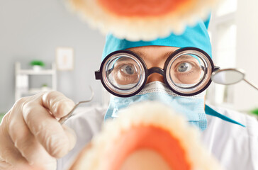 Funny dentist examines and treats a patient oral cavity and jaw at dental clinic. With a focus on dental health, the doctor orthodontist using instruments for tooth care and ensure a healthy smile.