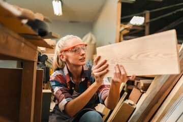 In a bustling carpenter's shop, a young woman craftsman expertly navigates her workshop, merging...
