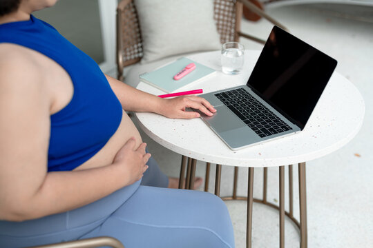 Cropped images of a pregnant woman using laptop computer at home