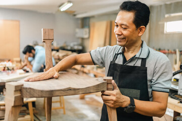 Carpenter working with electric planer on wooden plank in workshop. Craftsman makes own successful...